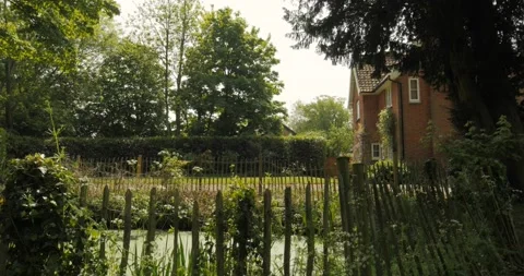 Cottage seen over pond with rustic fence Video stock 153527392