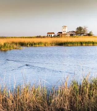 Cottage surrounded by stubble fields by the river under a moody, cloudy sky Stock Photos