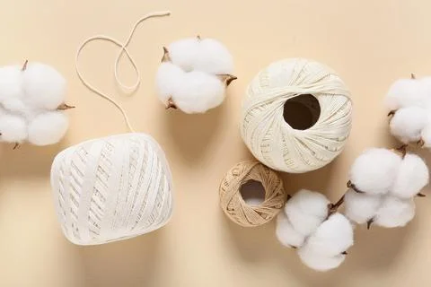 Cotton bolls and balls of thread on beige background Stock Photos
