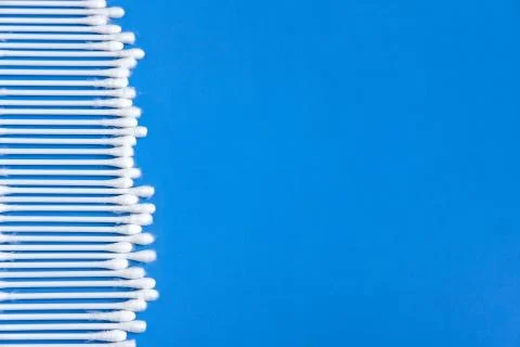 Cotton buds on the left on a blue background. Stock Photos
