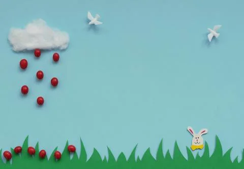 Cotton cloud with the rain of small red Easter eggs falling on green grass, E Stock Photos