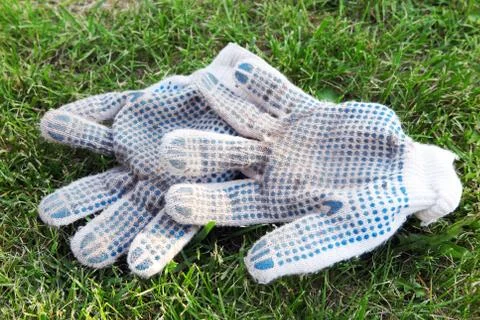 Cotton knitted work gloves lying on the mown lawn in the garden Stock Photos