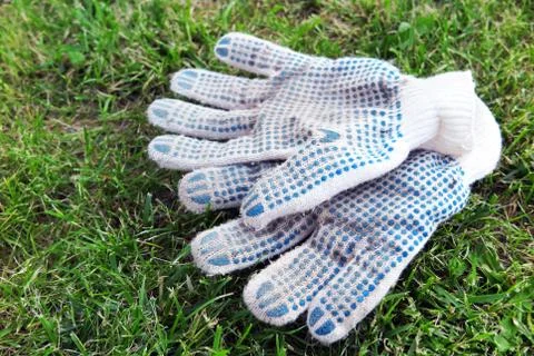Cotton knitted work gloves lying on the mown lawn in the garden Fotos de archivo