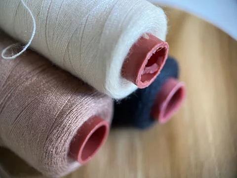 Cotton thread on spool for sewing material with wood background Stock Photos