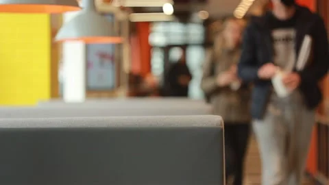 Couch in a cafe with blurry people passing by during the day time Видео 142930316