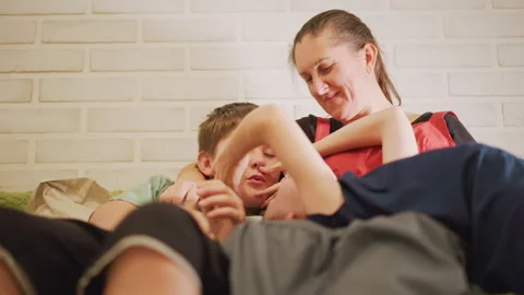 Couch snuggle with white home cook mother laughing with sons, playful tickling Stock Footage 346402556