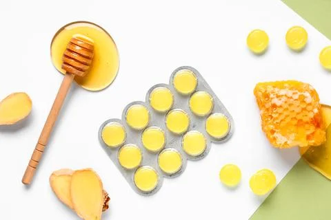 Cough drops in blister with ginger root slices, honeycomb and dipper on color Stock Photos