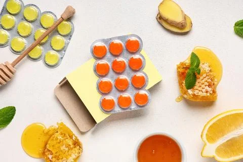 Cough drops in blisters with lemon, ginger root slices, bowl of honey and min Stock Photos