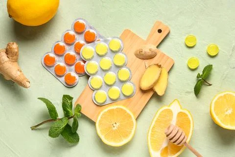 Cough drops in blisters with lemons, mint leaves and ginger root on green bac Stock Photos