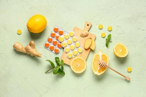 Cough drops in blisters with lemons, mint leaves and ginger root on green bac Stock Photos
