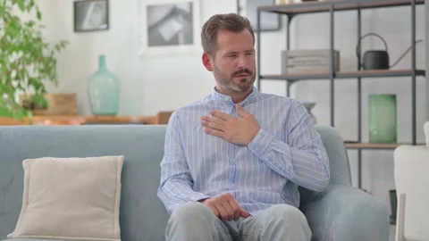 Coughing Middle Aged Man Sitting on Sofa at Home Stock Footage 287897622