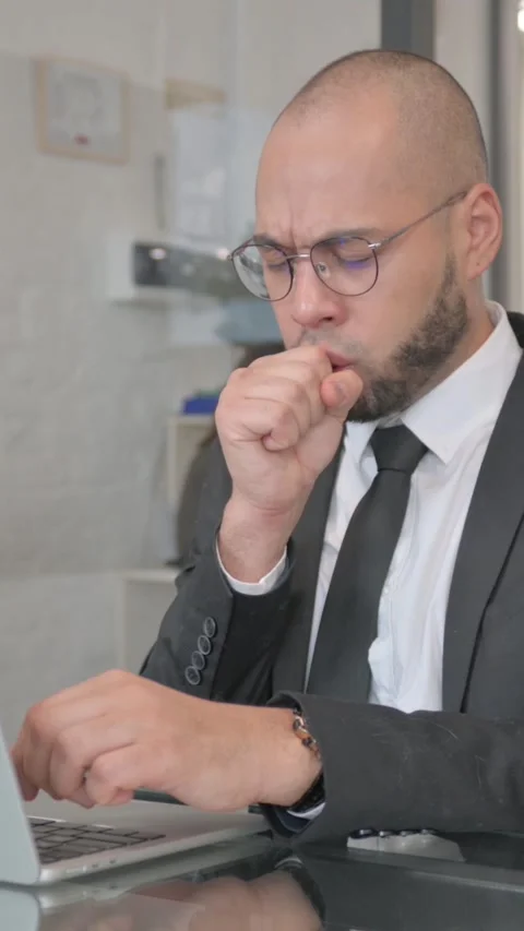 Coughing Mixed Race Businessman Using Laptop, vertical video 動画素材 325568281