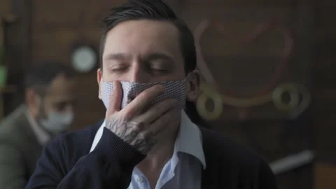 Coughing young freelancer in a protective mask is sitting in the office with Stock Footage 130602853