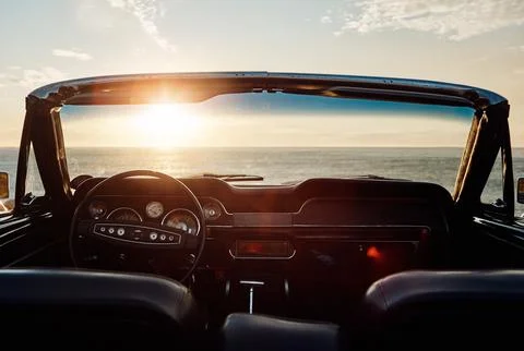 Could summer be more tempting. an empty vintage car parked along the coast at Stock Photos