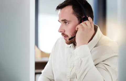 Could you repeat that. a handsome young call centre agent sitting alone in his Stock Photos