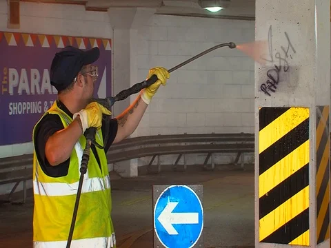 Council worker using high pressure water to remove graffiti on a pillar Stock Footage 103834721