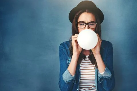 Countdown to party time. Studio shot of an attractive young woman blowing up a Foto stock