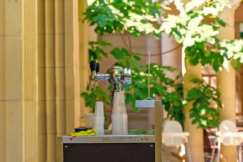 Counter with taps for bottling drinks, next to plastic cups Stock Photos