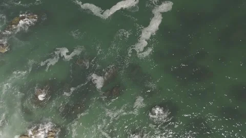 Counterclockwise accent of ocean waves onto rocks and beach Stock Footage 279775459