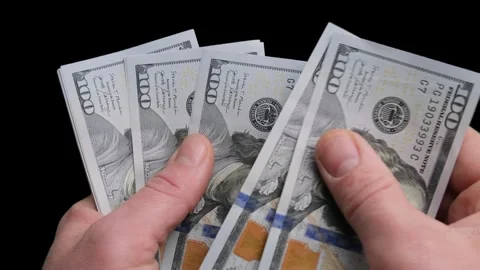Counting American banknotes on a black background. A man counts dollars. Stock Footage 260484085