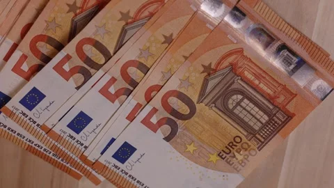 Counting multiple fifty euro notes on a smooth wooden table in a cozy indoor Stock Footage 318971831