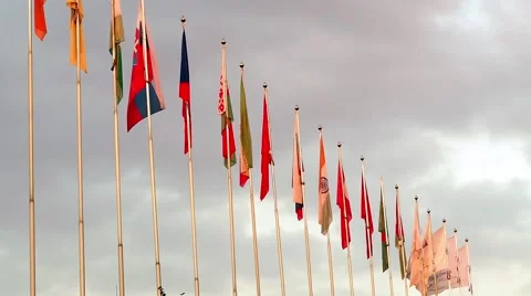 Countries and Corporate Flags Fluttering in the Wind Against a Blue Cloudy Sky Stock Footage 67314421