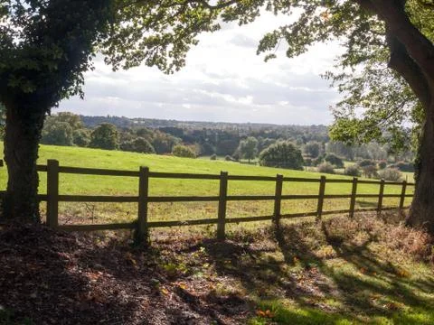 Country side open rolling fields below with wooden fence up front Stock Photos