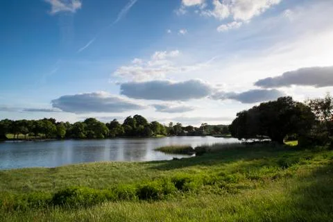 Countryside landscape over fields to calm lake wth blue sky Stock Photos
