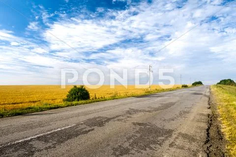 Countryside road among fields. Beautiful cloudy sky Stock Photos