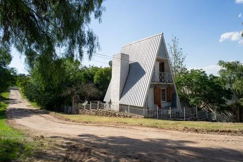 Countryside shot of triangular frame house, A-shaped hut near rural road on sunn 스톡 사진