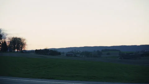 Countryside at sunset pan across fields and farm house Stock Footage 276380519