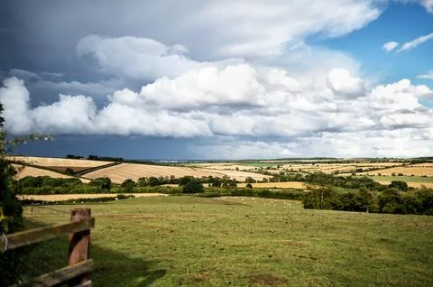 Countryside view to dramatic storm clouds over wheat field. Stock Photos