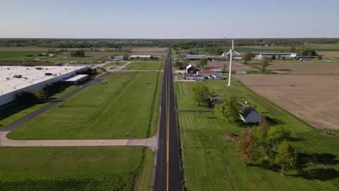 County road through the small town. farm and wind turbines Stock Footage 244351727