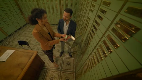 A couple accessing a secure deposit box in a bank vault to examine their Stock Footage 278690160