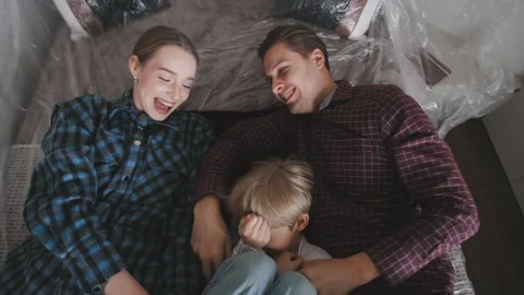 A couple and their son are falling on a bed in their new home. They are moving Stock Footage 346227073