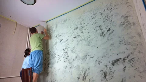 Couple applying wallpaper to interior wall near floor in timelapse Stock Footage 335319076
