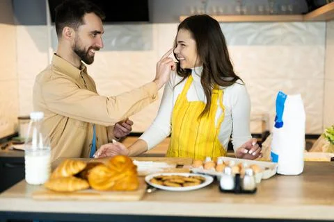 Couple are having fun while cooking. They seem happy being together in the Stock Photos
