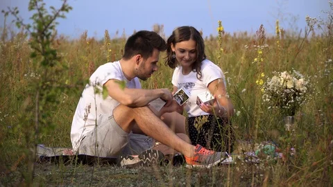 A couple are looking at paper cubes with their photos among a summer field 動画素材 127289910