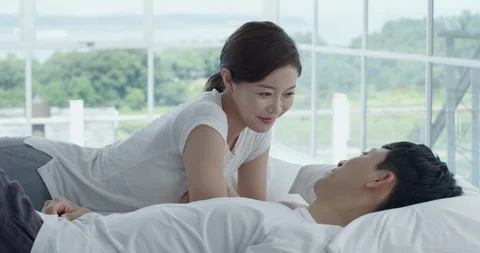 The couple are lying in bed, talking to each other, smiling Stock Footage 100937674