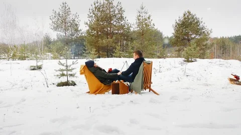 The couple are sitting by the bonfire in the winter forest in comfortable 스톡 동영상 100014101