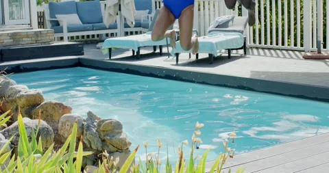 Couple are walking, reaching pool edge and leaping into backyard pool beside Stock Footage 340881874