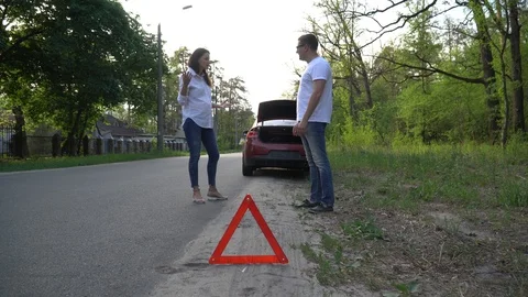 Couple arguing in front of broken down car on quiet country road. Stock Footage 92044912