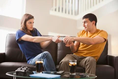 Couple arguing over remote on sofa Fotos Stock
