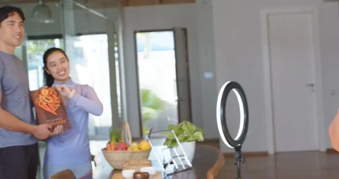 Couple arranging cookbook on stand at table while photographer framing DSLR, for 스톡 동영상 335906987