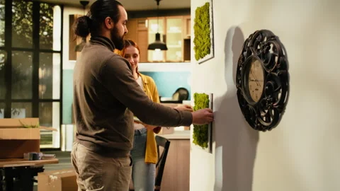 Couple arranging decorations and paintings on the wall in new house Stock Footage 342905552