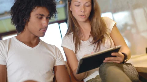 Couple of attractive young people use tablet computer and communicate Video stock 40675053