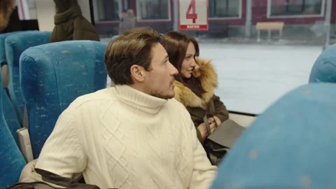 A couple of average people take off their outerwear in their seats in the train Stock Footage 199518494