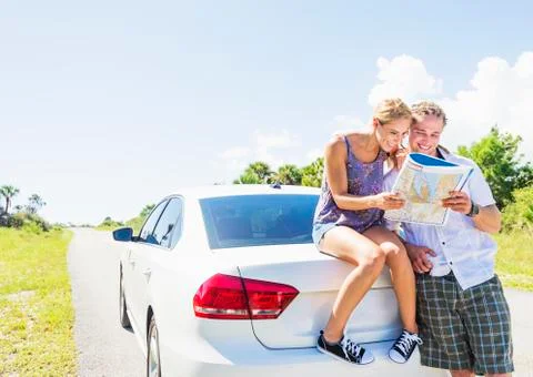 Couple at back of car looking at map Fotos Stock