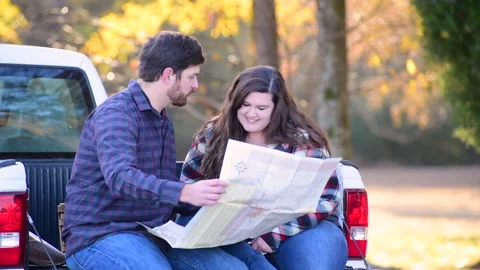 Couple at the back of a pick-up planning a trip while enjoying the fall colors 库存影片 143429997