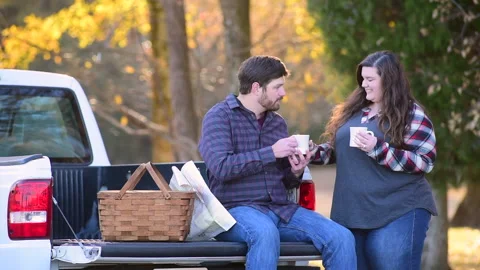 Couple at the back of a pick-up planning a trip while enjoying the fall colors 库存影片 143430138